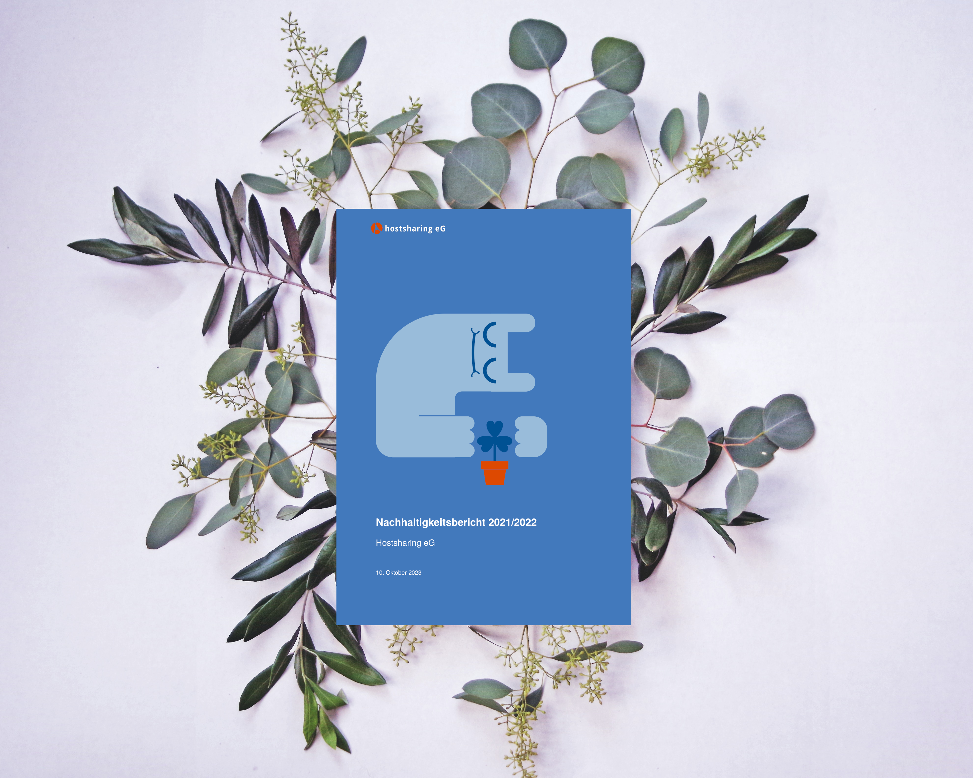Der Nachhaltigkeitsbericht liegt auf fein arrangierten Blättern. Das Cover zeigt das Hostsharing-Maskottchen, das sich schützend über eine Blume beugt.