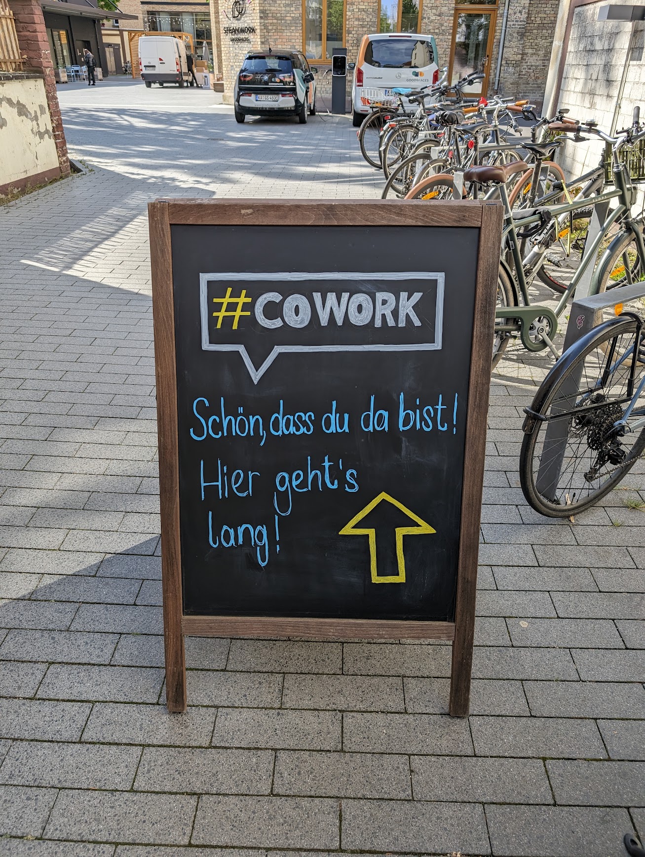 Aufsteller mit Hinweis: #COWORK. Schön, dass du da bist. Hier geht's lang.