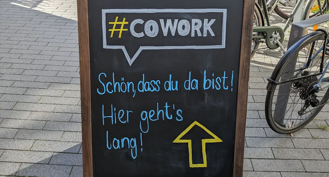Aufsteller mit Hinweis: #COWORK. Schön, dass du da bist. Hier geht's lang.