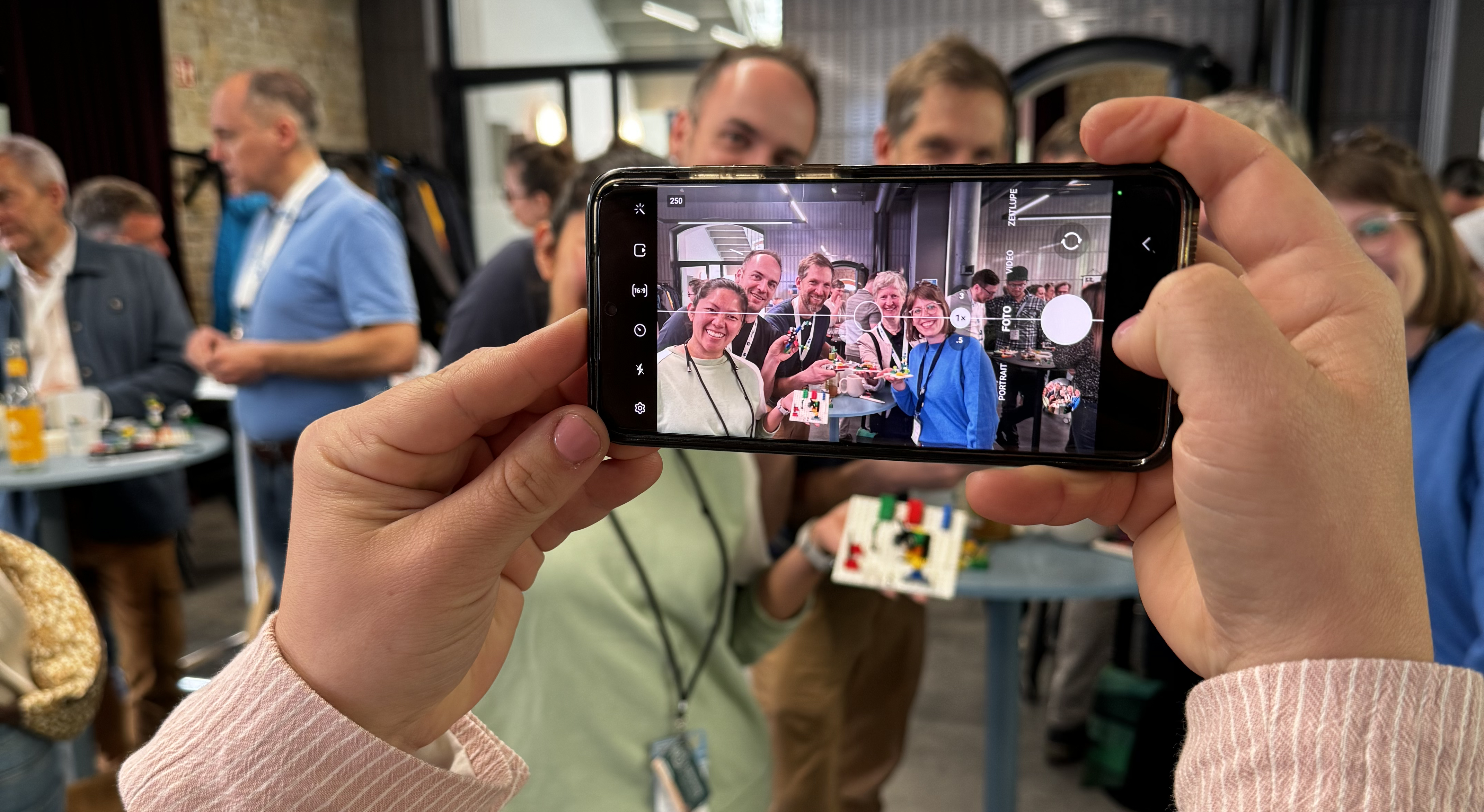 Mit dem Smartphone wird eine Gruppe fotografiert, die mit Lego spielt.