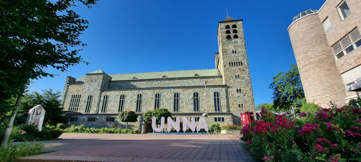 Schriftzug ›Unna‹ vor einer Kirche.