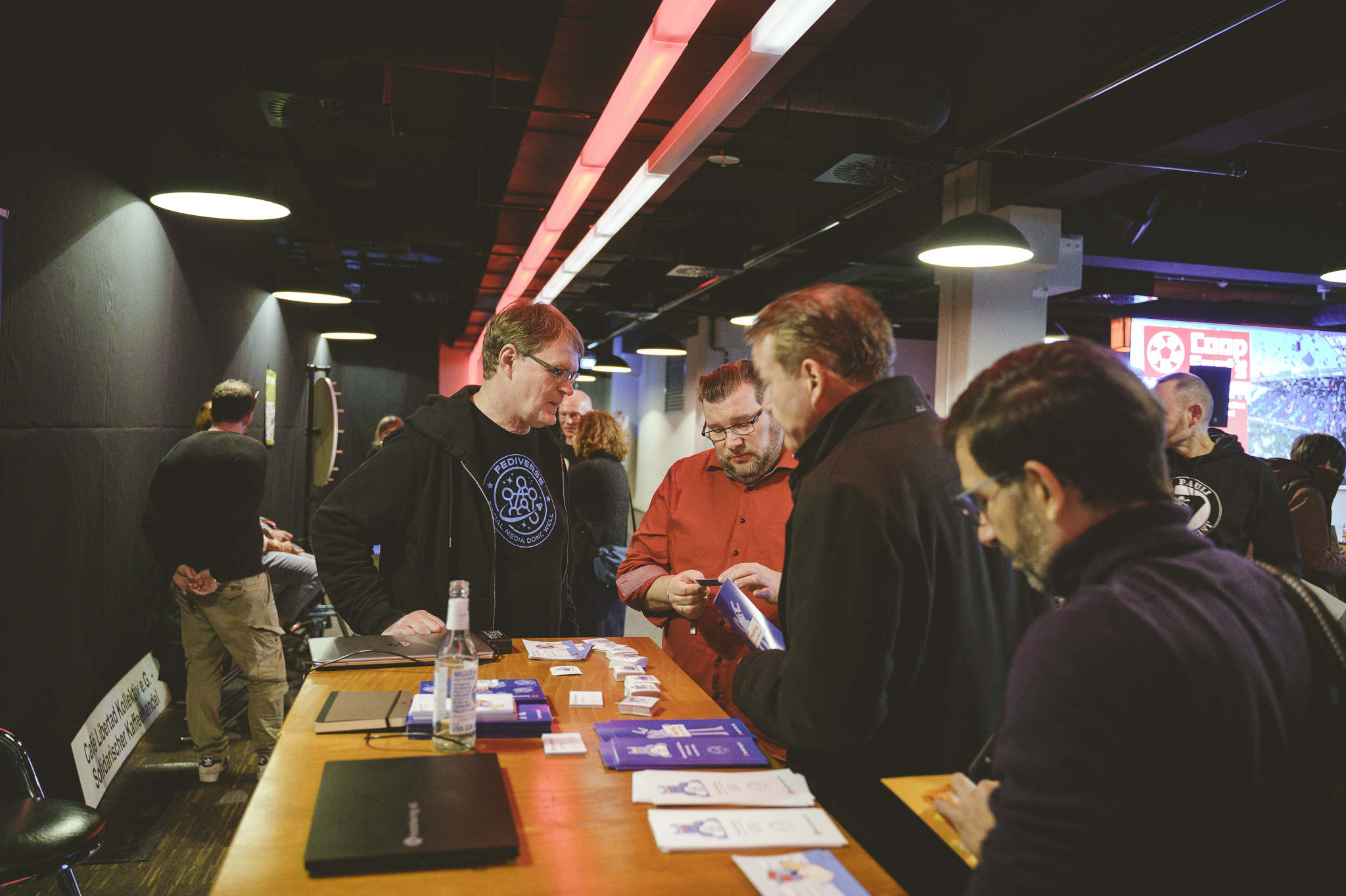 Mehrere Personen an einem Stehtisch, auf dem Flyer liegen.
