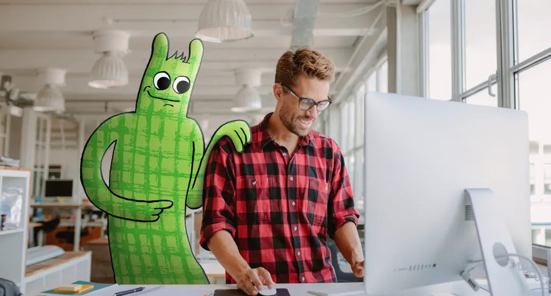 Mann arbeitet am Computer, hinter ihm steht das Hostsharing-Maskottchen.