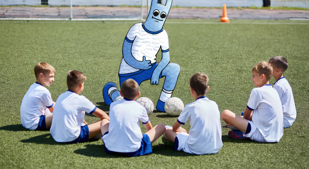 Wir helfen Vereinen bei der selbstbestimmten Digitalisierung Eine Fußball-Mannschaft. Das Hostsharing-Maskottchen als Trainer.