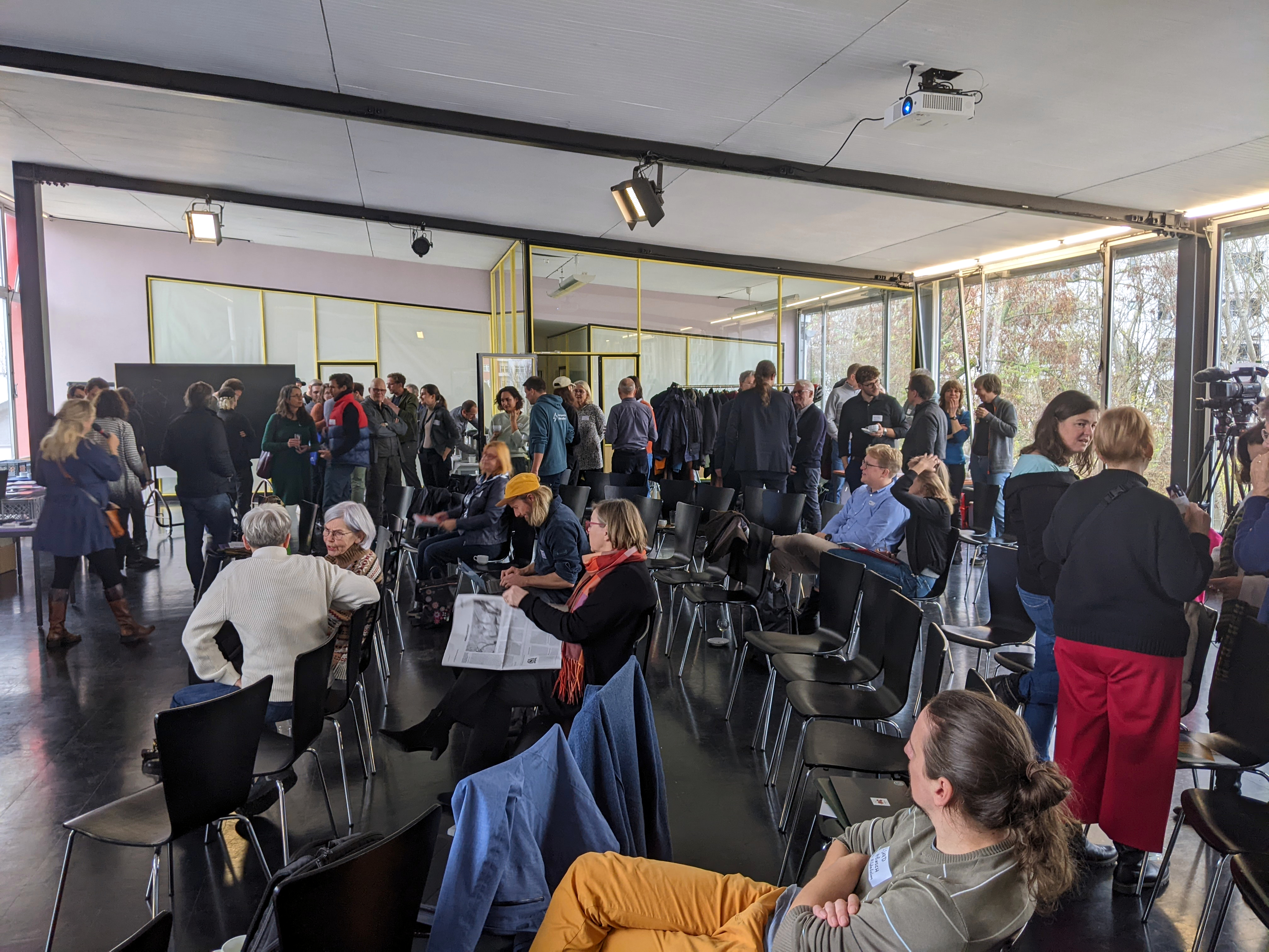 Viele Menschen in einem Saal mit großen Fenstern