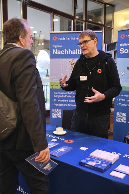 Zwei Männer stehen im Gespräch, hinter ihnen ein Aufsteller: Digitale Nachhaltigkeit.