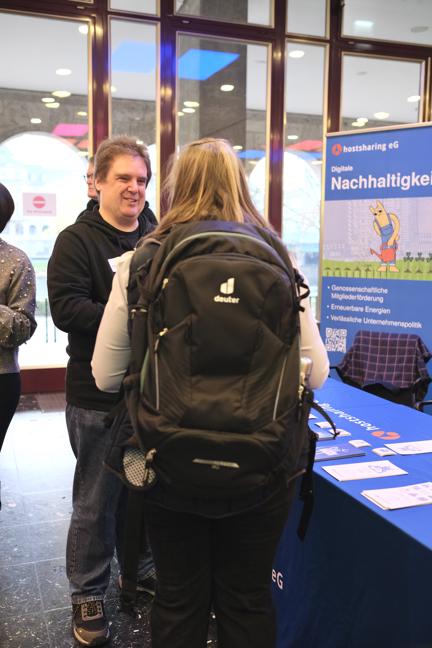 Zwei Männer stehen im Gespräch, hinter ihnen ein Aufsteller: Digitale Nachhaltigkeit