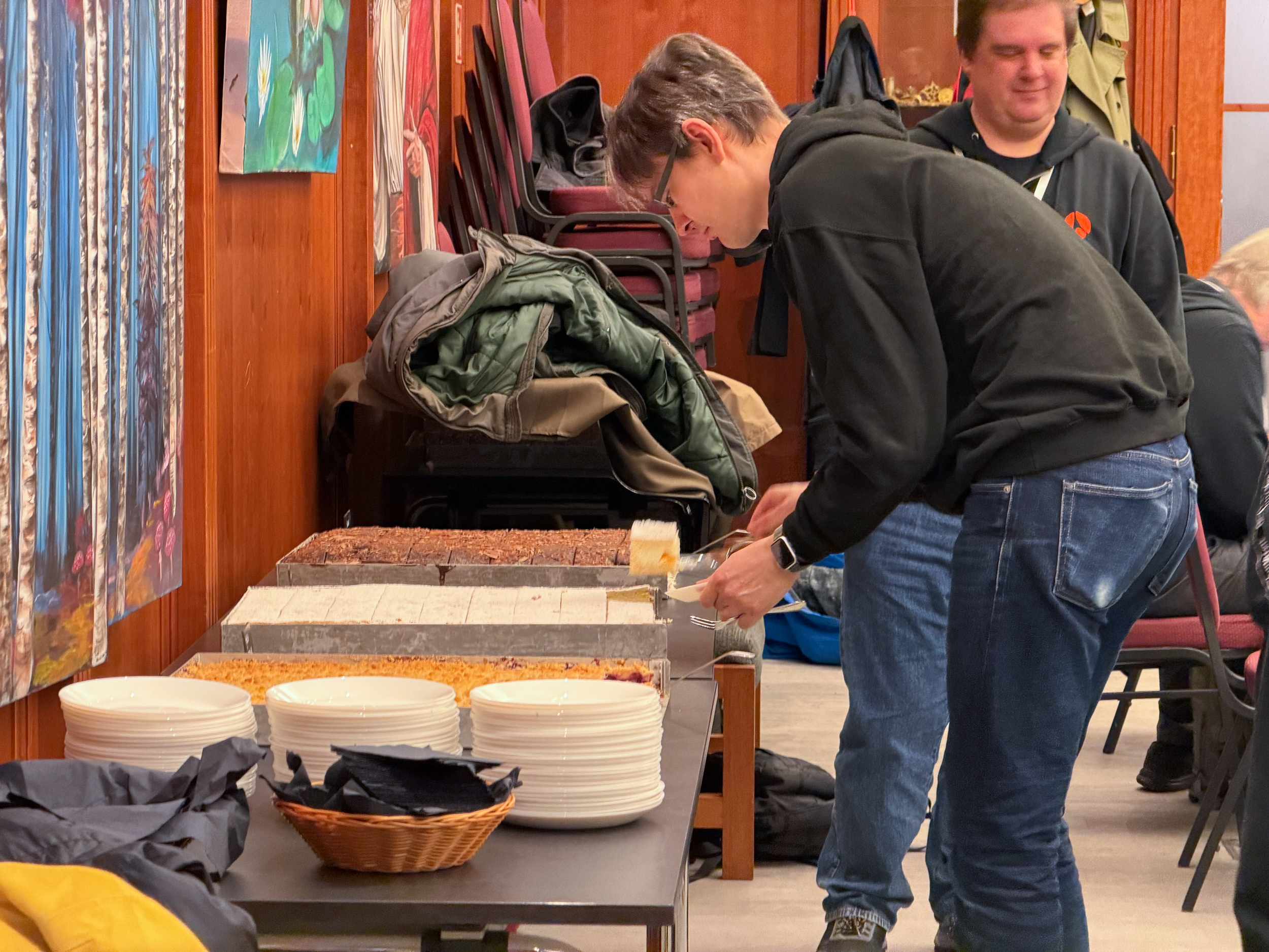 Eine männliche Person nimmt sich mit von einem Blech ein Stück Kuchen