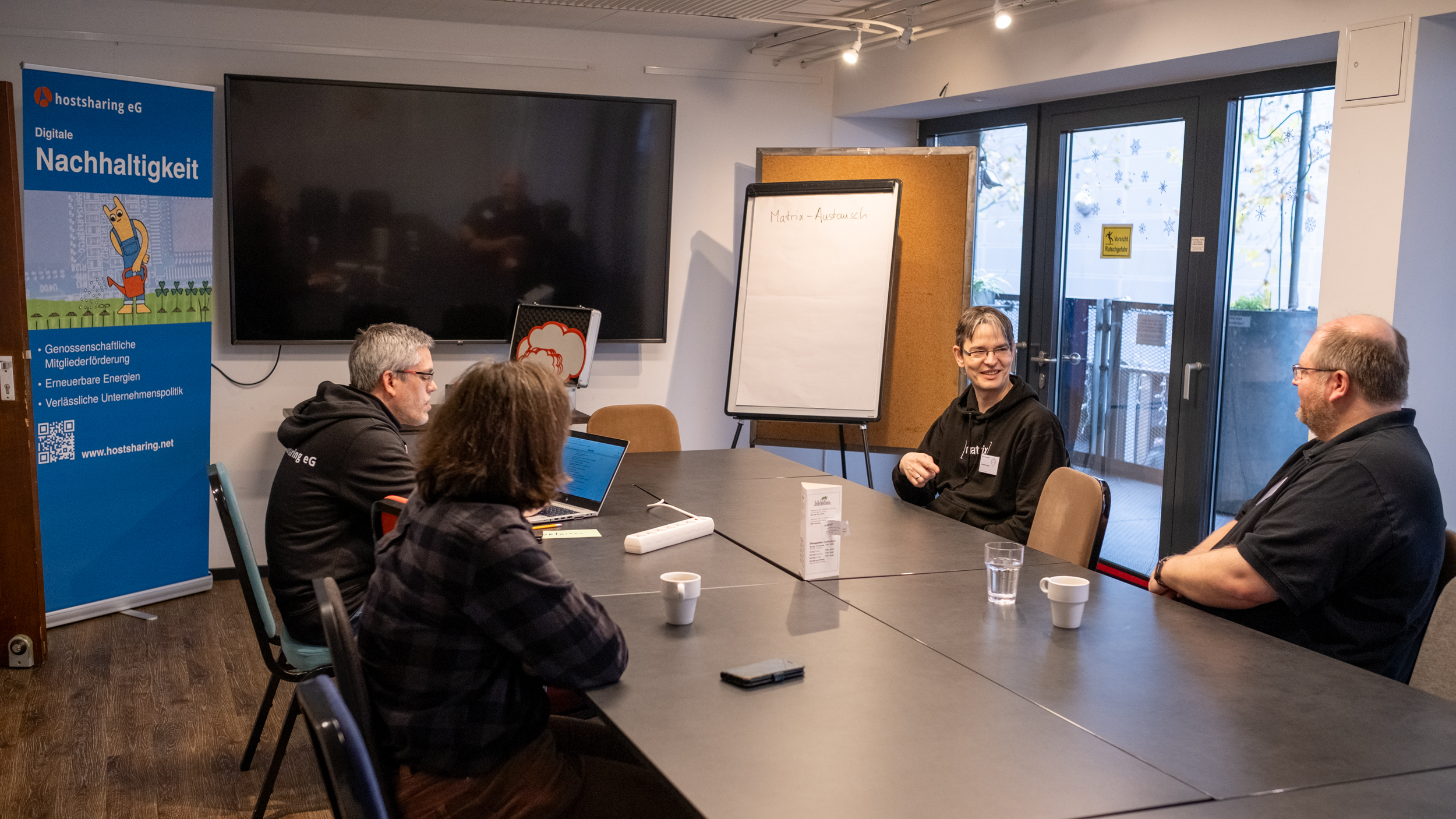 Vier Personen sitzen in einem Seminarraum und reden.