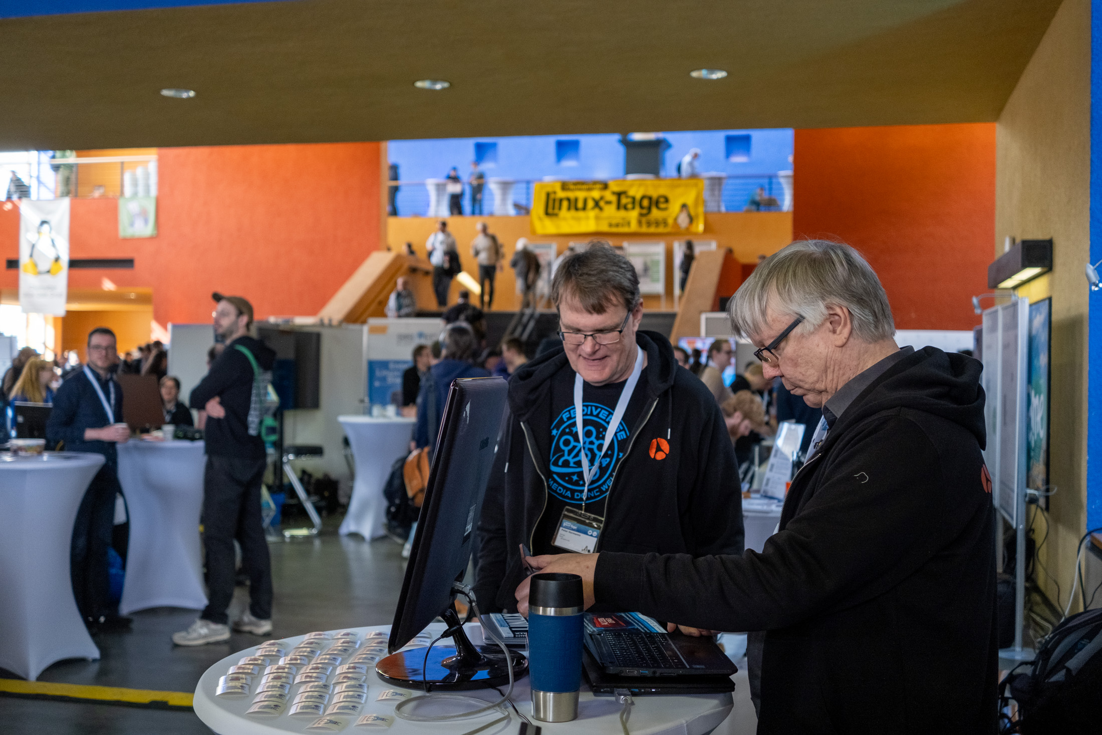 Zwei Männer stehen an einem Tisch und arbeiten an Notebooks.