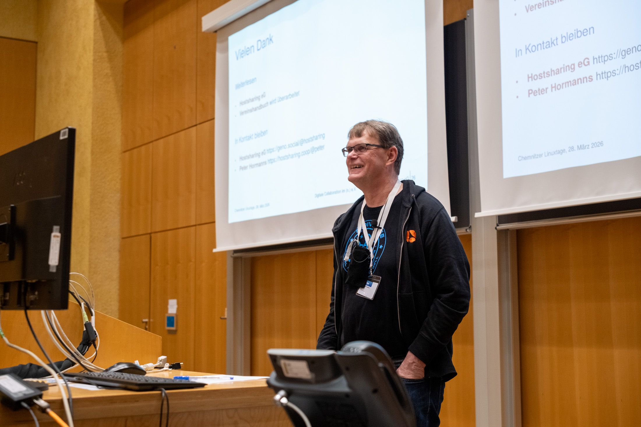 Ein Mann steht lächelnd vor einem Rednerpult. Hinter ihm zwei Projektionsleinwände