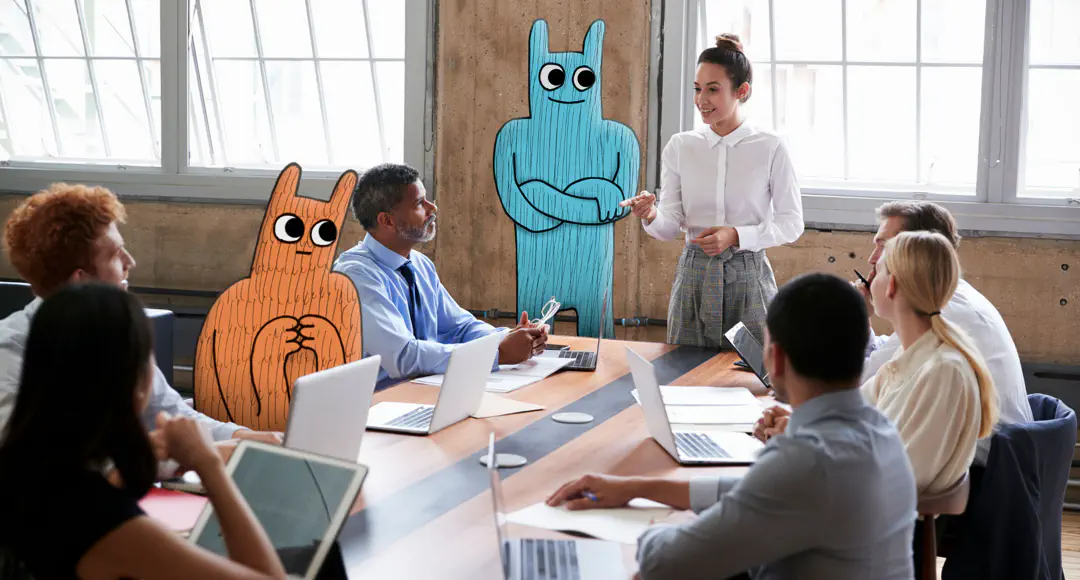 Hostsharing unterstützt Agenturen. Meeting. Eine Frau spricht zu Kollegen, unter denen sich zwei Hostsharing-Maskottchen befinden.