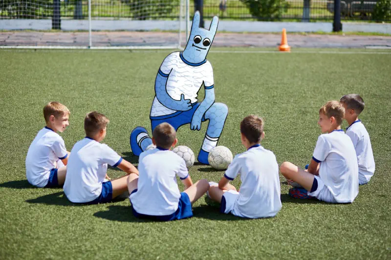 Das Hostsharing-Maskottchen steht wie ein Trainer vor einer Fußballjugendmannschaft.