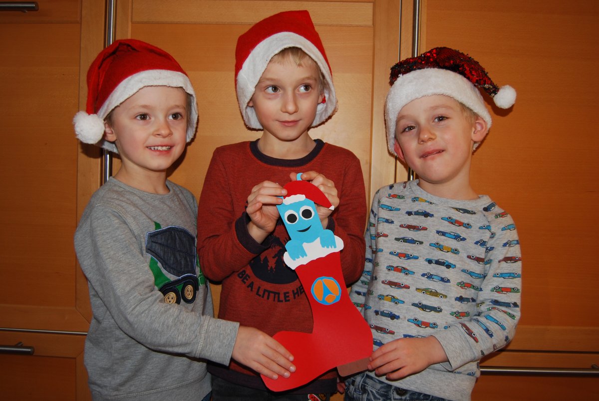 Drei Kinder haben einen Nikolaus-Stiefel gebastelt, in dem das Hostsharing-Maskottchen steckt.