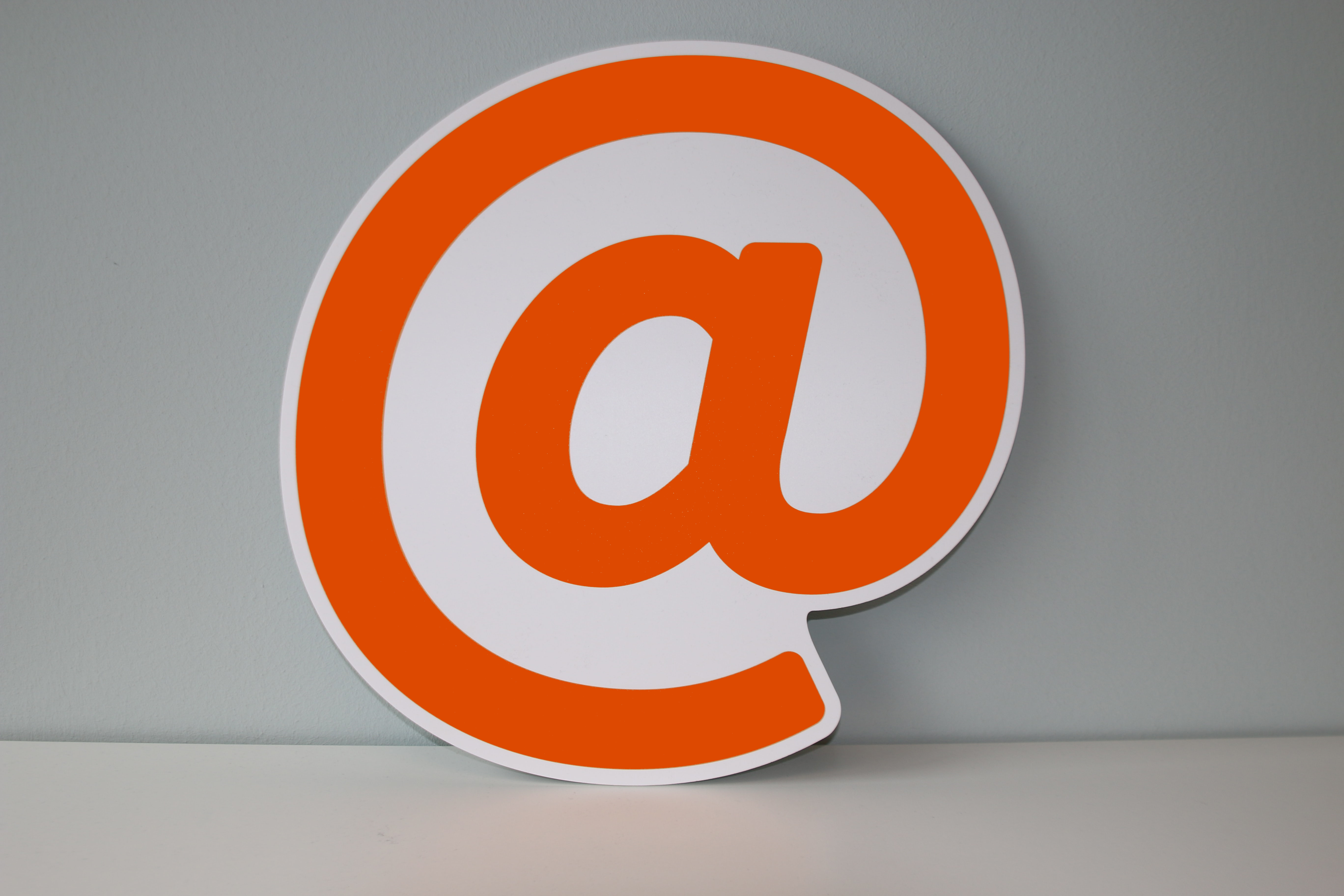 Orangefarbenes @-Symbol vor grauem Hintergrund