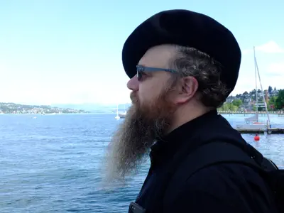 Mann mit Brille, Bart und Baskenmütze im Profil