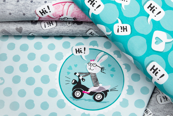 Bunte Stoffe in hellen Farben. Aufgedruckt ein Häschen auf Motorrad. Sprechblasen sagen: Hi!