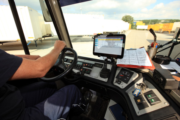 LKW-Fahrer in seiner Kabine, die Hände am Lenkrad. Auf dem Armaturenbrett ein fest montiertes Tablet